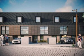A modern building with a flat roof, multiple windows, and a paved entrance area. - 3 Bed in Hayle (oc-b584309) (Hayle)