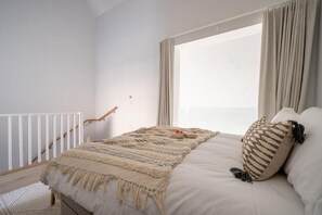 A bedroom with a bed, a window with curtains, a white railing, and a small table with a bowl. - 3 Bed in Hayle (oc-b584309) (Hayle)