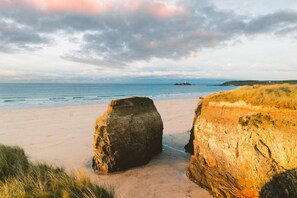 A beach with two large rock formations in the foreground and a lighthouse in the distance. - 3 Bed in Hayle (oc-b584309) (Hayle)