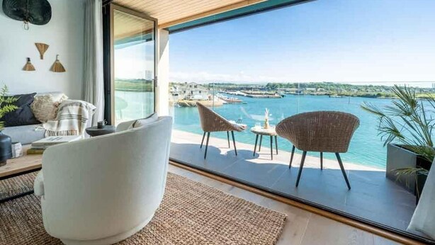 A modern interior with a large glass door leading to a balcony overlooking a marina. - 3 Bed in Hayle (oc-b584309) (Hayle)