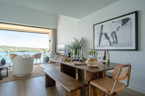 Een moderne eetruimte met een houten tafel, stoelen en uitzicht op zee.