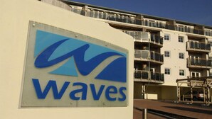 En bygning med et skilt, der står 'Waves', og en høj boligbygning med altaner i baggrunden.