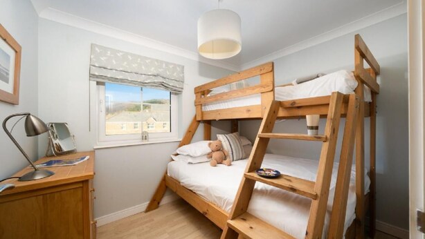 Et soveværelse med køjeseng, skrivebord, lampe og vindue med udsigt.