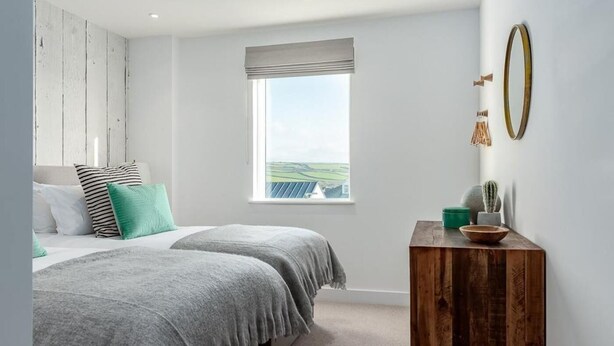 Een slaapkamer met twee bedden, een raam met uitzicht, een houten dressoir en een spiegel.