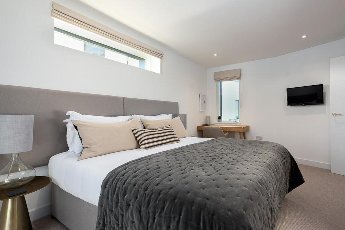 Een moderne slaapkamer met een groot bed, nachtkastjes, een bureau en een televisie.
