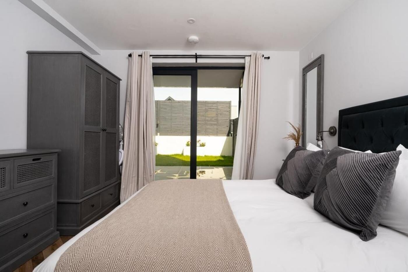 A bedroom with a bed, a wardrobe, and a sliding glass door leading to a patio.