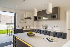 A modern kitchen with a central island, pendant lighting, and built-in cabinetry. - 2 Bed in Bude (oc-b588786) (Bude)