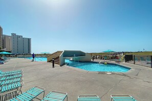 A pool area with lounge chairs and a small waterfall feature. - Phoenix VII #1509 -- New! 2BR Beachfront, Insane Gulf Views, Pool, Hot Tub, Gym (Orange Beach)
