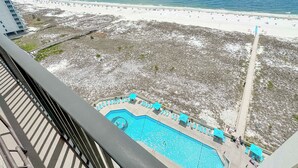 Blick auf einen Strand mit Schwimmbad, einem Steg und einem Gebäude im Hintergrund.