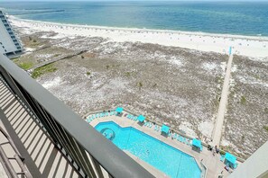 Blick auf einen Strand mit Schwimmbad, einem Steg und einem Gebäude im Hintergrund.