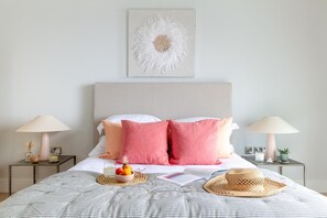 A neatly made bed with a striped bedspread, two bedside tables with lamps, and a wall-mounted artwork. - 4 Bed in Fistral (oc-b584261) (Newquay)
