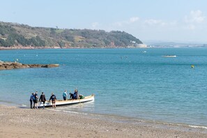 Ein Strand mit einem Boot und Menschen am Ufer.