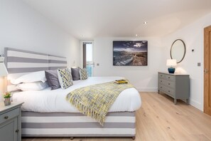 Ein modernes Schlafzimmer mit einem großen Bett, Nachttischen, einem Schminktisch und einem Bild an der Wand.