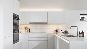 Eine moderne Küche mit weißen Schränken, einem eingebauten Ofen und einer Edelstahl-Spüle.