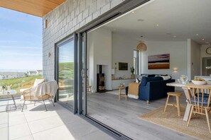 Ein stilvolles Wohnzimmer mit Glastür zum Balkon, einer Sofagruppe, einem Essbereich und einem Kamin.