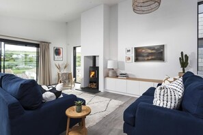Una sala de estar moderna con chimenea, un conjunto de sofás, una mesita auxiliar y vistas al exterior.