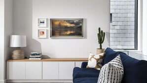 Ein Wohnzimmer mit einem blauen Sofa, einer Lampe, einem Kaktus und einem Bücherregal.