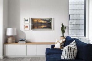 Ein Wohnzimmer mit einem blauen Sofa, einer Lampe, einem Kaktus und einem Bücherregal.