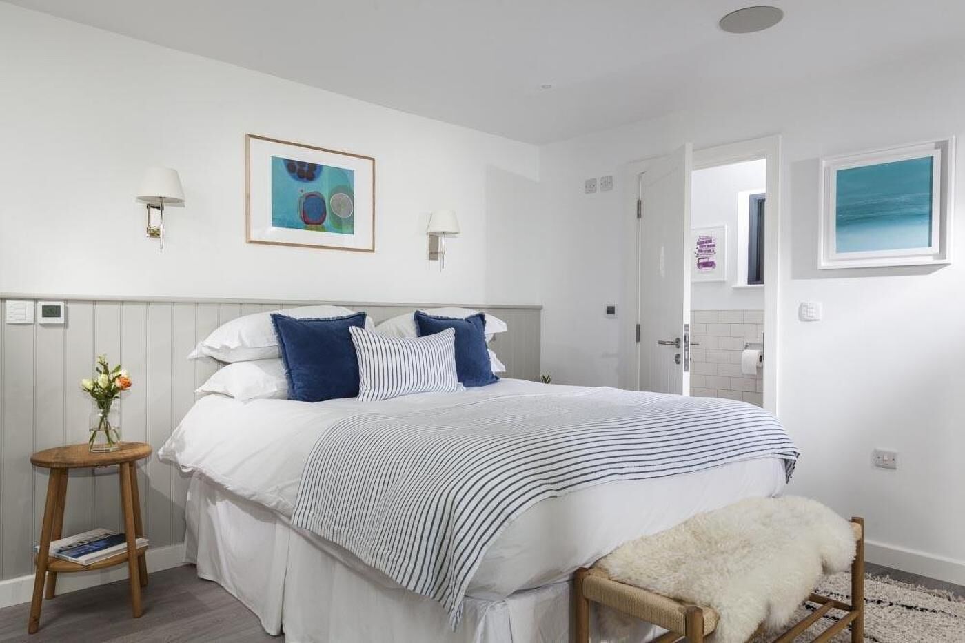 A bedroom with a bed, bedside tables, a chair, and artwork on the walls.