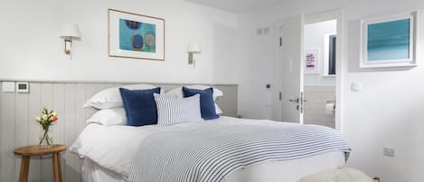 A bedroom with a bed, bedside tables, a chair, and artwork on the walls.
