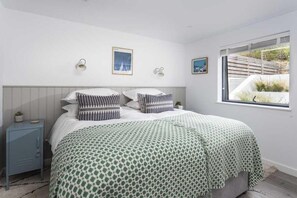 Ein Schlafzimmer mit einem Bett, einem Nachttisch, Wandlampen und einem Fenster mit Blick.