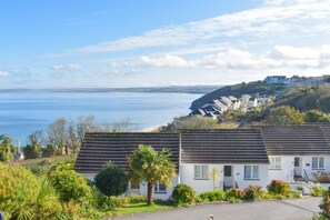A coastal residential area with houses, a clear sky, and a view of the sea. - 2 Bed in Carbis Bay (oc-b584272) (Carbis Bay)