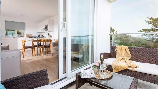 Een modern appartement met balkon, een eethoek en een woonruimte met een bank en tafel.