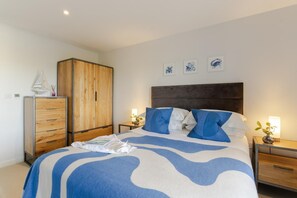 Ein Schlafzimmer mit einem Bett, einem Kleiderschrank, Nachttischen und Wandbildern.