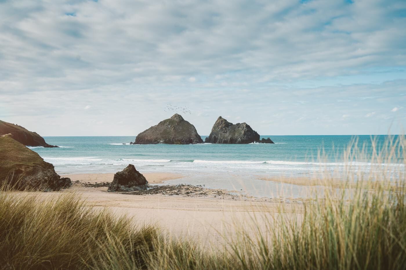 A beach with two prominent rock formations and a clear sky.