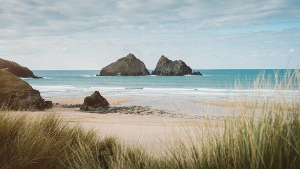 A beach with two prominent rock formations and a clear sky. - 4 Bed in Holywell Bay (oc-b659846) (Holywell)