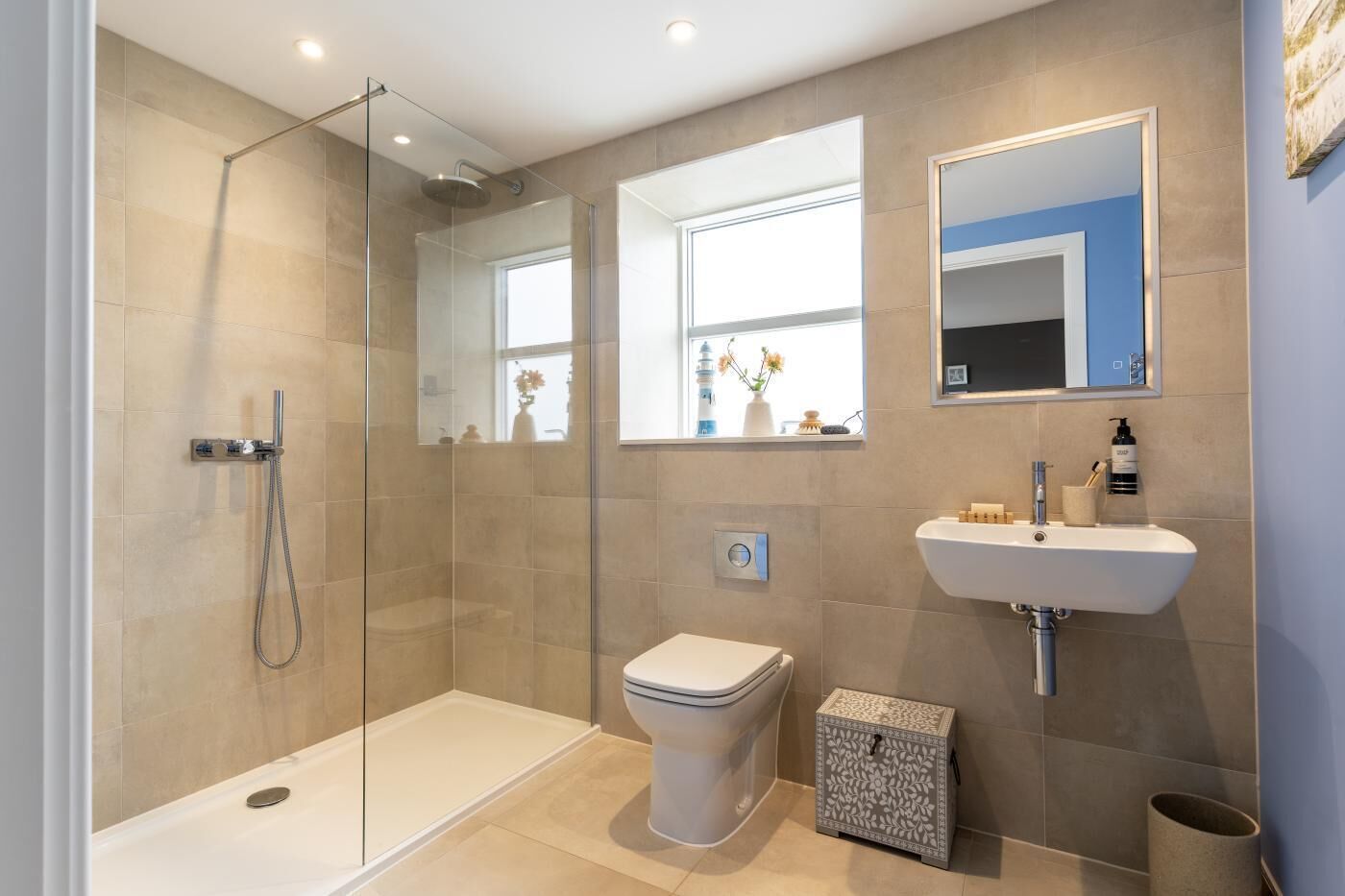 A modern bathroom with a glass-enclosed shower, a toilet, a sink, and a small decorative box.