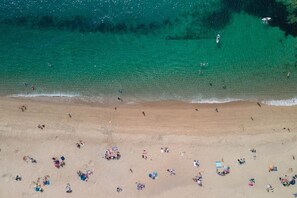 An aerial view of a beach with people and beach chairs. - 3 Bed in Carlyon Bay (oc-b623421) (Carlyon Bay)