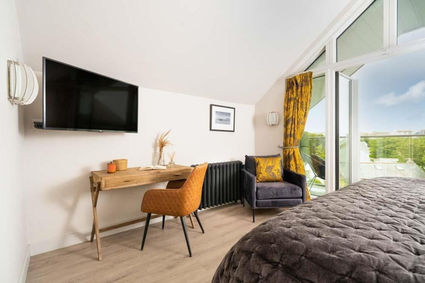 Ein modernes Hotelzimmer mit einem großen Bett, einem Schreibtisch mit Stuhl, einem Flachbildfernseher und einem Fenster mit Blick.