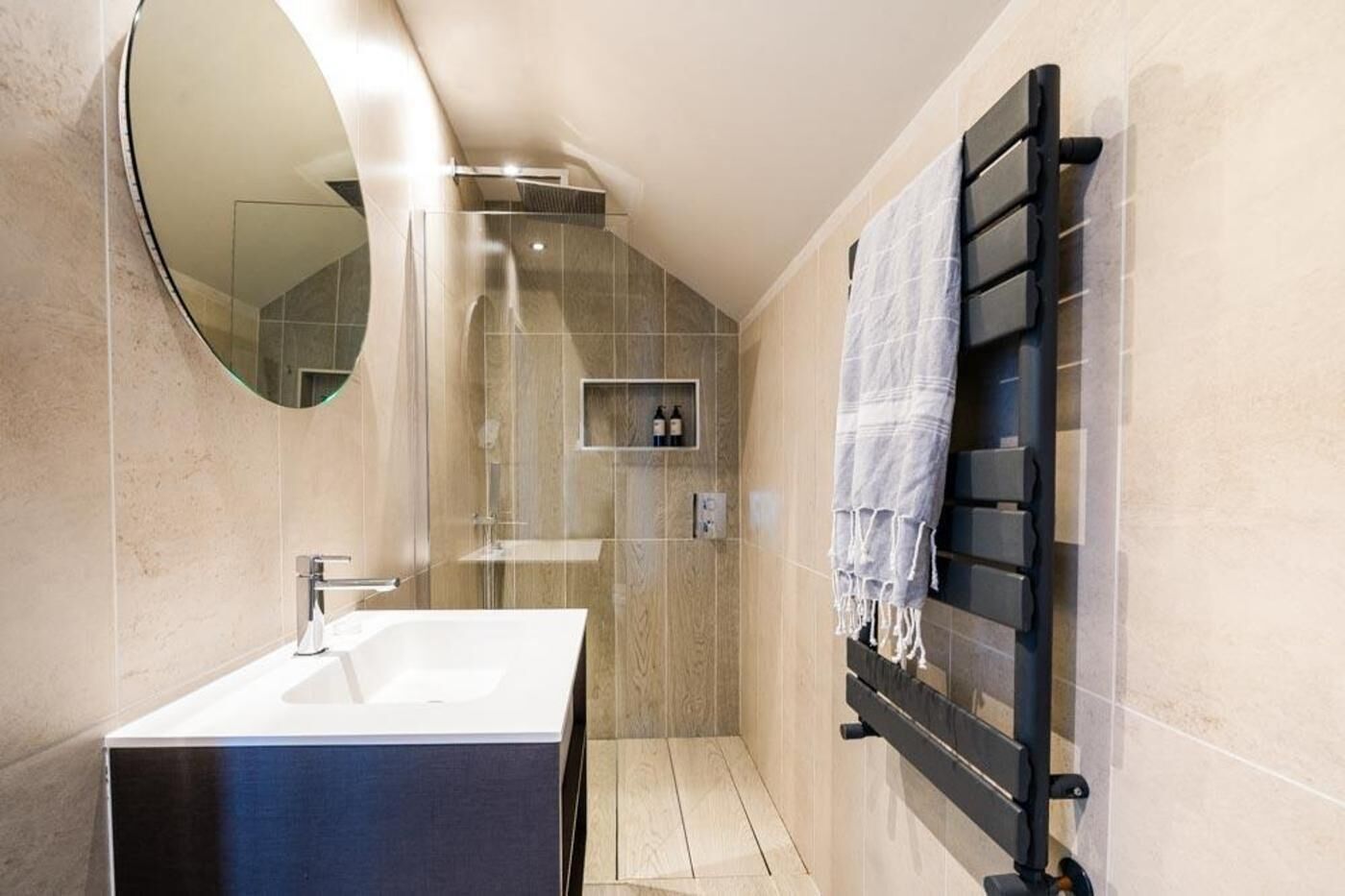A modern bathroom with a large mirror, a sink, and a towel rack.