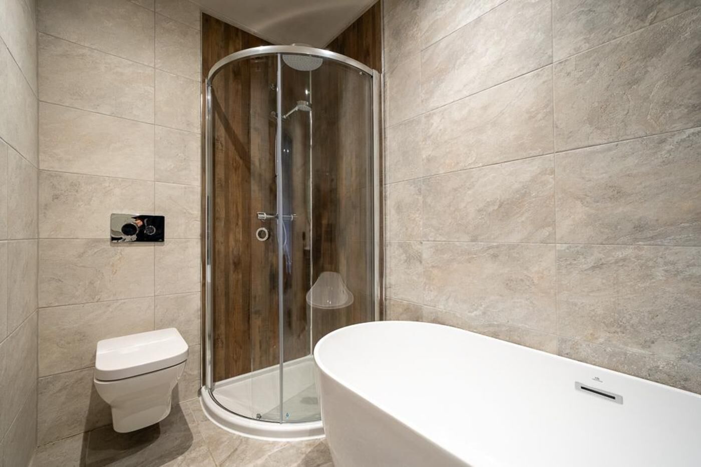 A modern bathroom with a glass-enclosed shower, a toilet, and a freestanding bathtub.