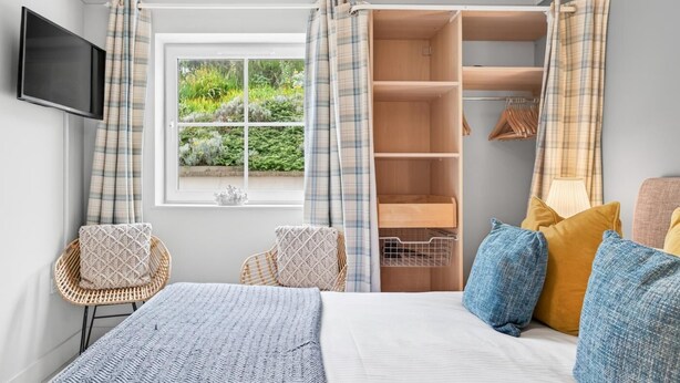 A bedroom with a bed, a wardrobe, a television, and a window with curtains. - 2 Bed in Watergate Bay (oc-b598859) (Tregurrian)