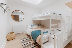 A bunk bed room with a white radiator, a woven basket, and a striped rug. - 3 Bed in Cawsand (oc-b588795) (Kingsand)