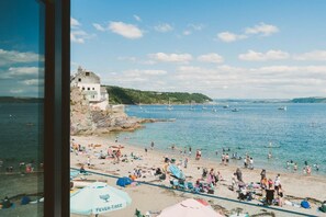 Ein Strand mit Menschen, Booten und einem Gebäude auf einer Klippe.