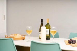 A dining table with two glasses of white wine, a loaf of bread, a bottle of wine, and a candle. - 3 Bed in Mawgan Porth (oc-b584450) (Mawgan Porth)