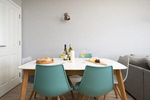 A dining area with a white table, teal chairs, and a white door in the background. - 3 Bed in Mawgan Porth (oc-b584450) (Mawgan Porth)