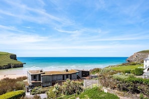 A coastal property with a modern house, a beach, and a cliff. - 3 Bed in Mawgan Porth (oc-b584450) (Mawgan Porth)