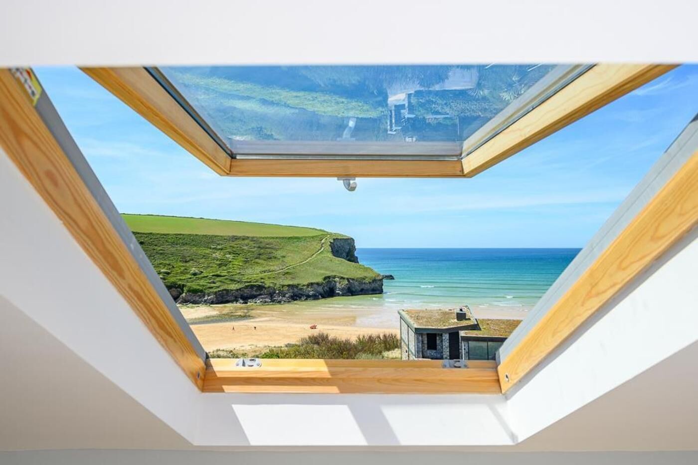 A skylight with a view of a beach and cliffs.