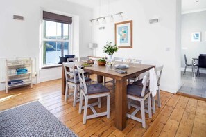 A dining area with a wooden table, six chairs, and a bookshelf. - 4 Bed in Fowey (oc-b584335) (Fowey)