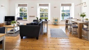 A spacious living area with a sofa, a dining table, and a TV. - 4 Bed in Fowey (oc-b584335) (Fowey)
