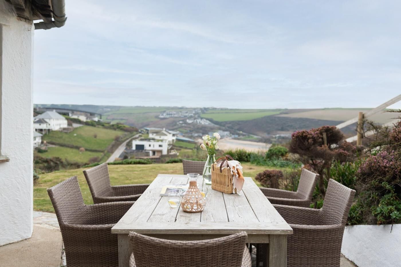 Een rieten tafel met vier stoelen op een terras met uitzicht op een schilderachtig landschap.