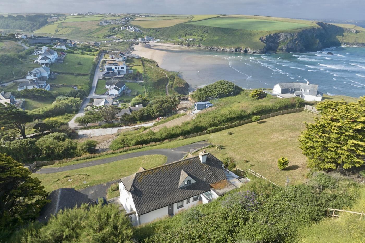 A coastal residential area with houses, a beach, and cliffs.