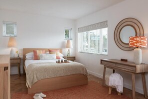A bedroom with a wooden bed, bedside tables, a desk, a mirror, and a window with blinds. - 4 Bed in Mawgan Porth (oc-b650080) (Mawgan Porth)