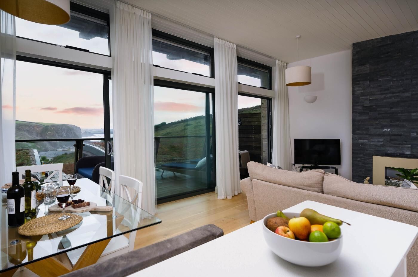 A modern living room with a glass dining table, a sofa, and a television.