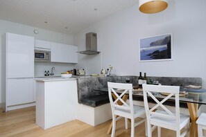 A modern kitchen with white cabinetry, a built-in microwave, and a grey countertop island. - 2 Bed in Watergate Bay (oc-b584340) (Tregurrian)