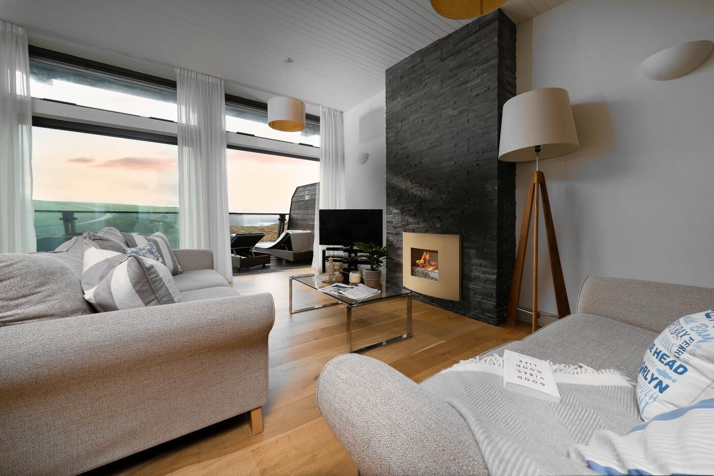 Ein modernes Wohnzimmer mit Kamin, Fernseher und einem Balkon mit Blick.